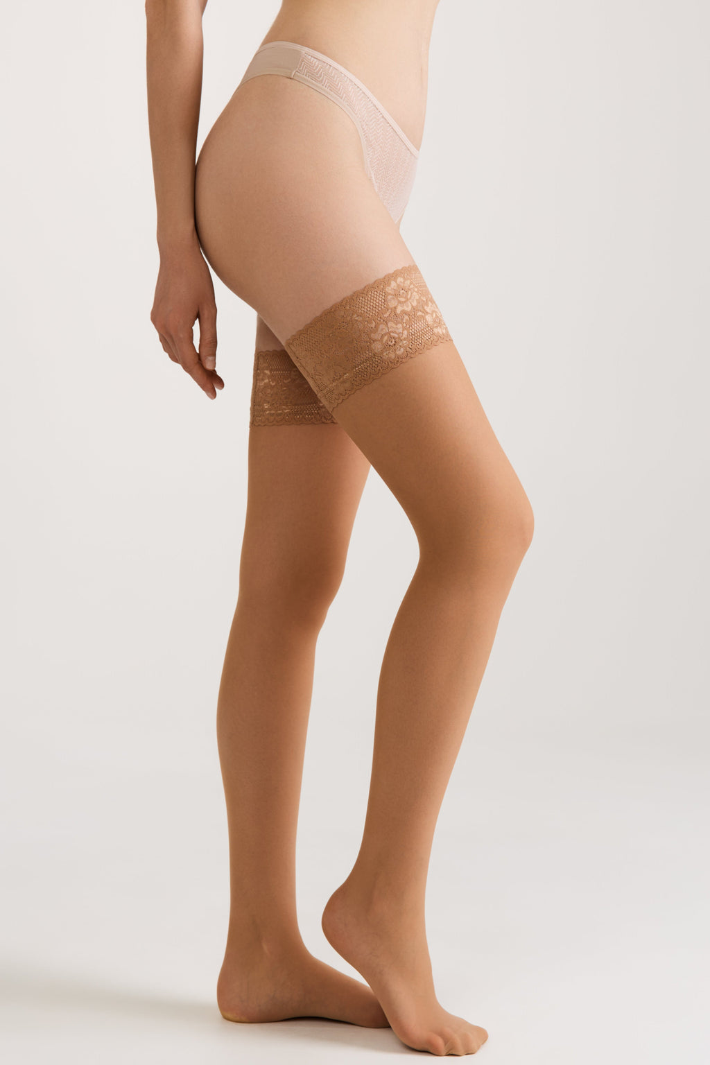 Tan sheer stockings with lace top band and silicone grip, side view on legs