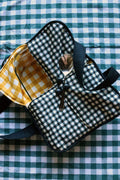 Plaid casserole carrier with padded handle and black strap, quilted exterior