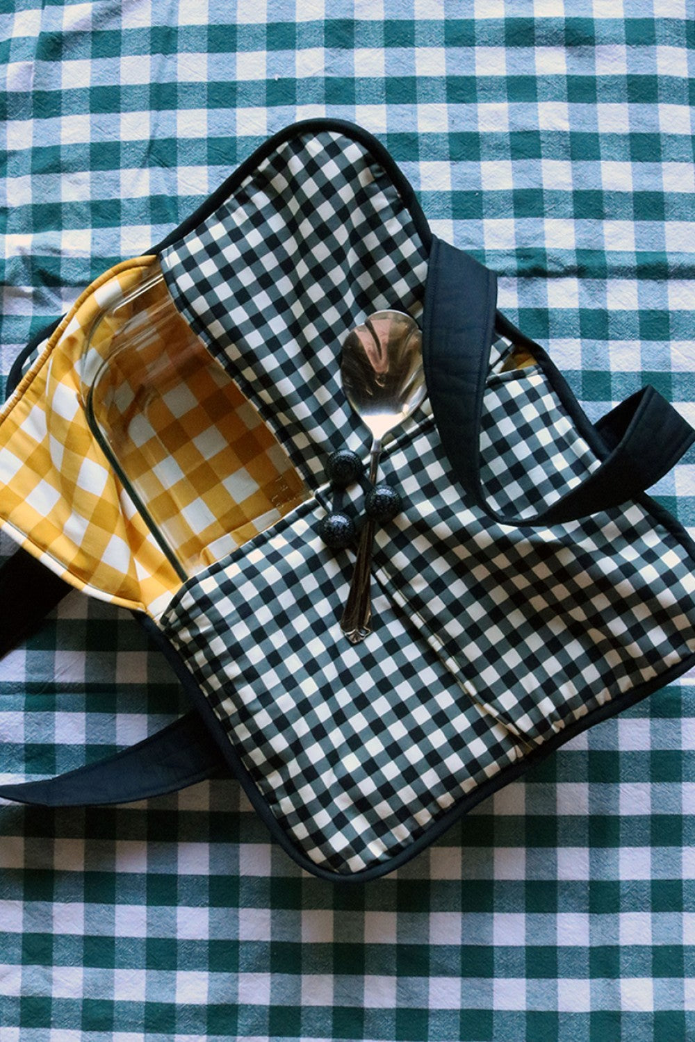 Plaid casserole carrier with padded handle and black strap, quilted exterior