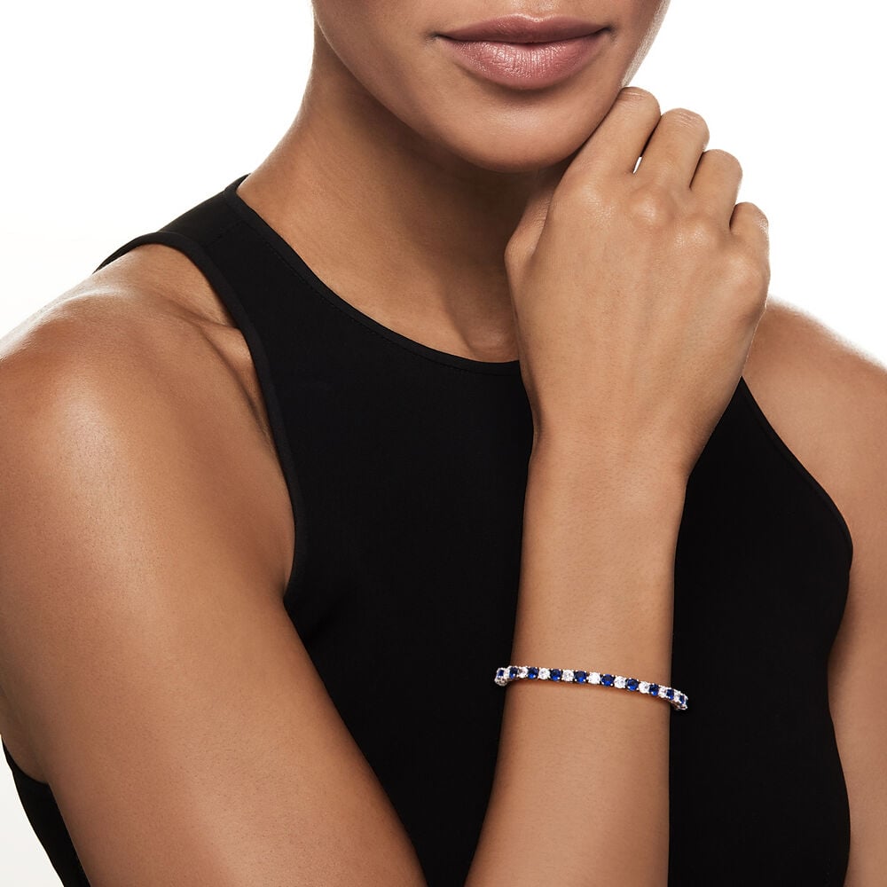 Blue and clear tennis bracelet on wrist, silvertone prong-set round stones