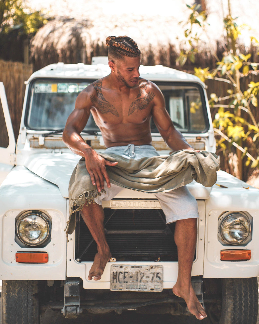 Olive-gray beach towel draped over shoulders with fringed hem, used outdoors.