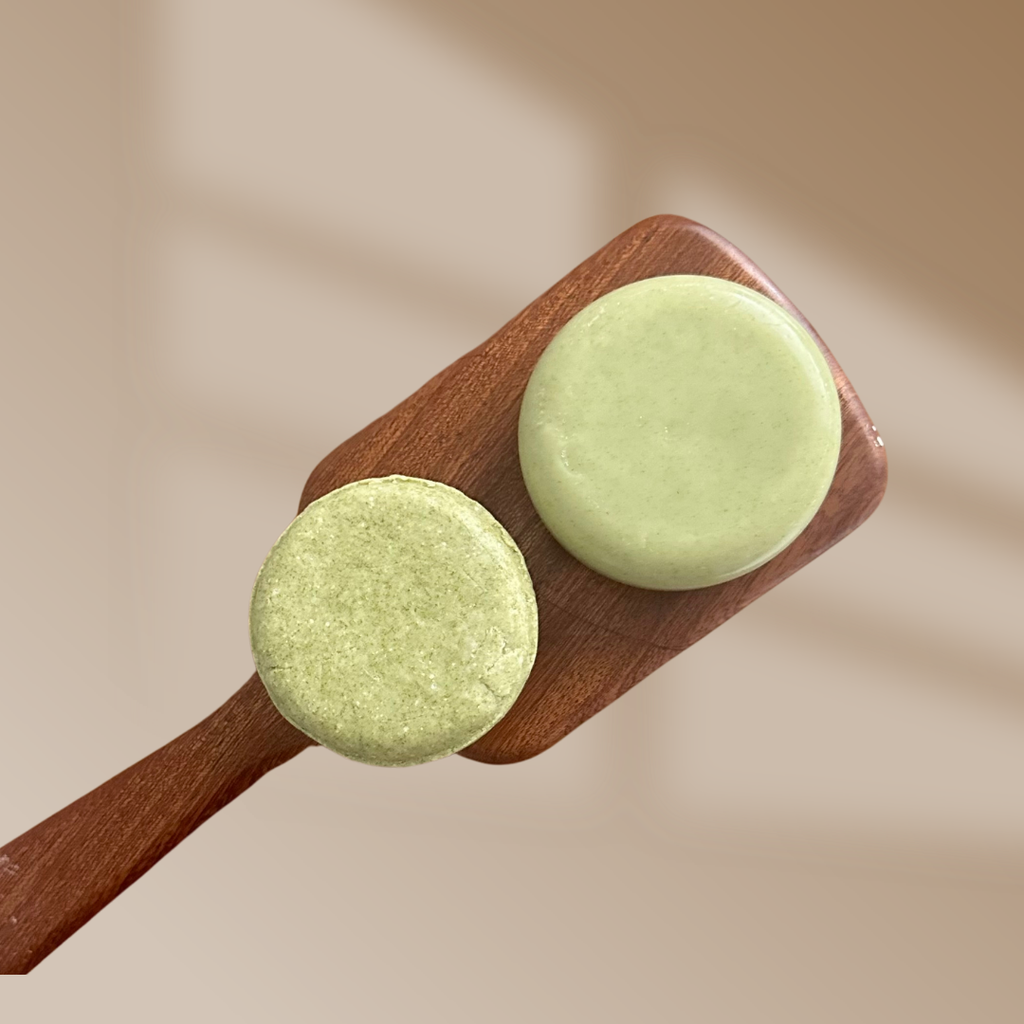 Two light green round shampoo bars on a wooden board