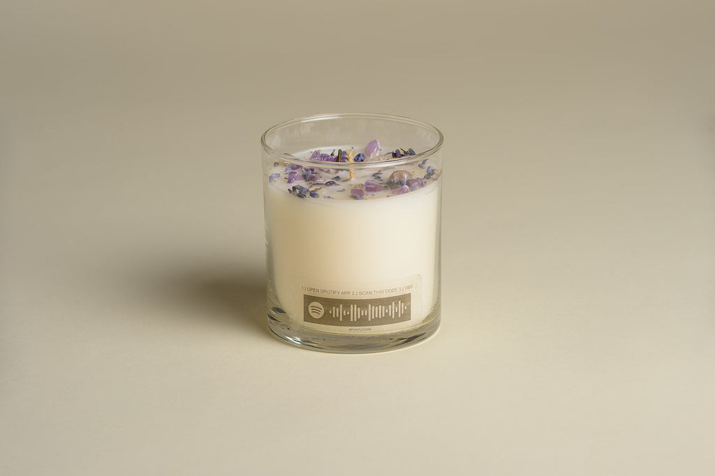 Glass jar candle with lavender buds scattered across the wax top