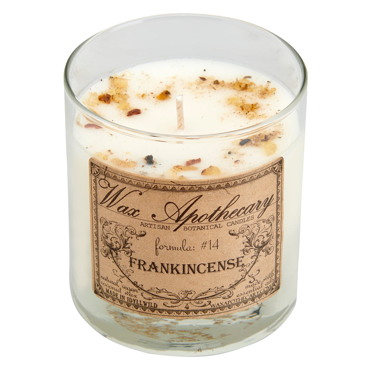 Clear scotch glass candle with Frankincense label and speckled wax near centered wick