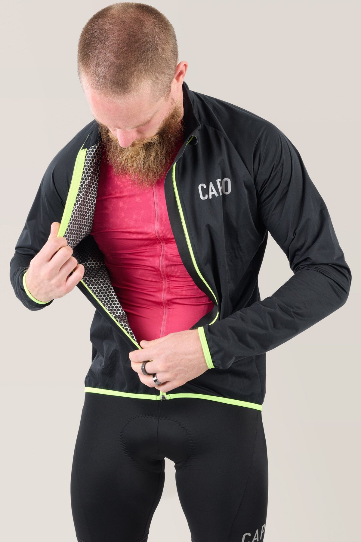 Black rain jacket open with neon lime trim, showing inner pink layer