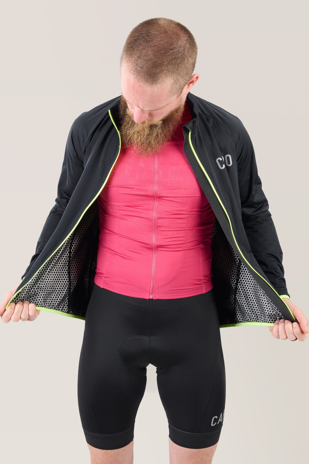 Black rain jacket with open mesh lining and neon lime piping, side view
