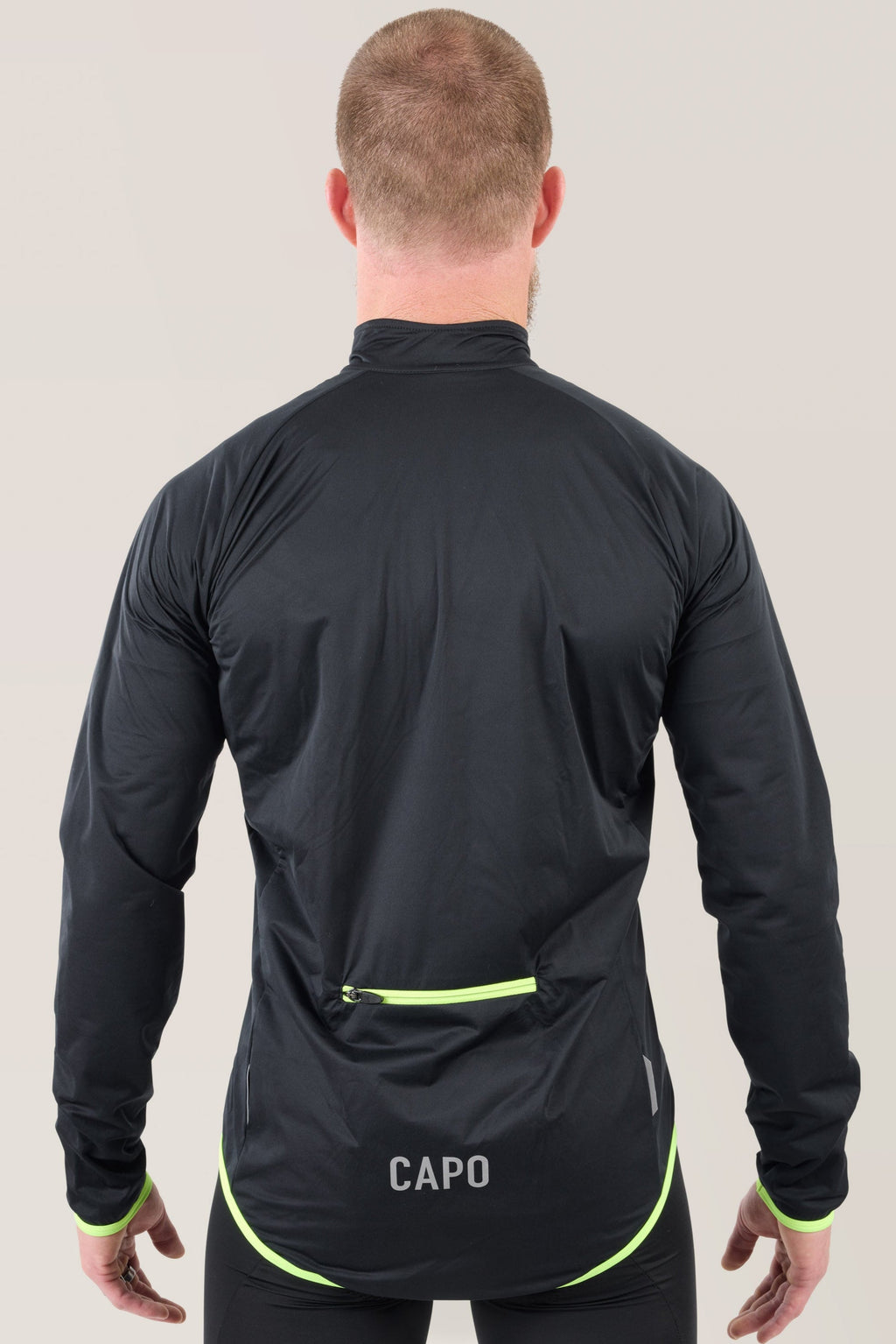Black rain jacket with neon lime trim and back zip pocket, rear view