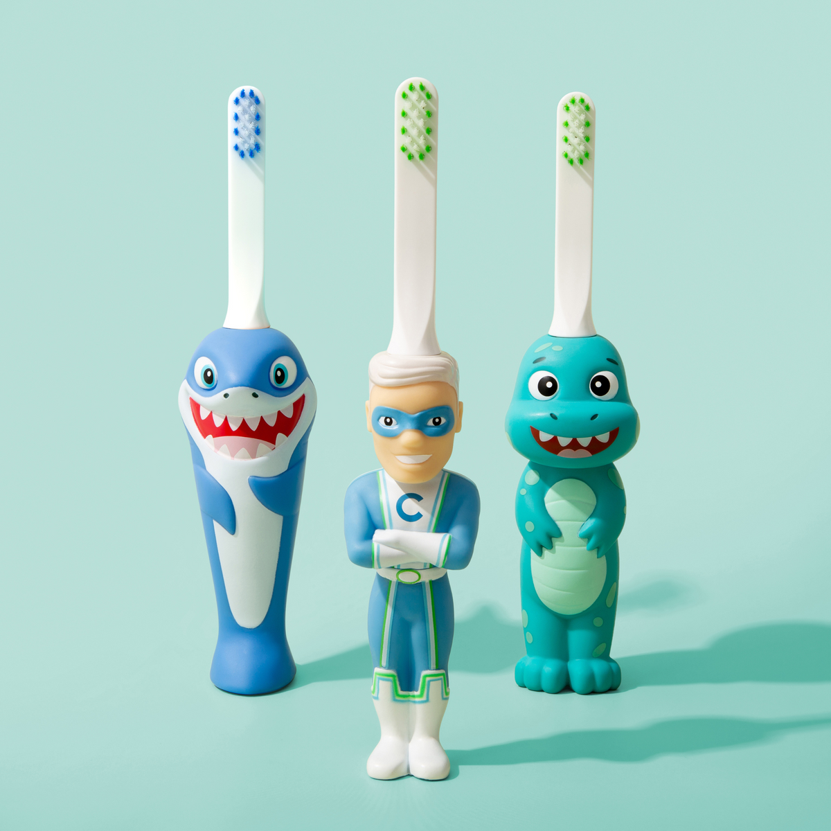 Set of three kids character toy toothbrushes with blue and green figure handles