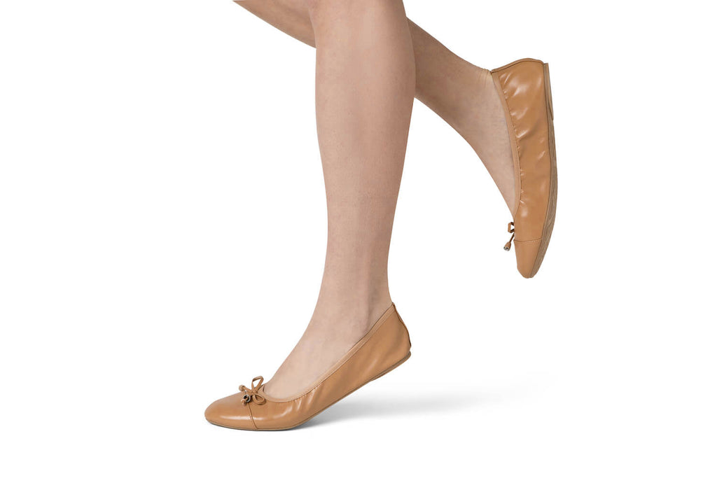 Caramel ballet flats with tie bows worn on model’s feet