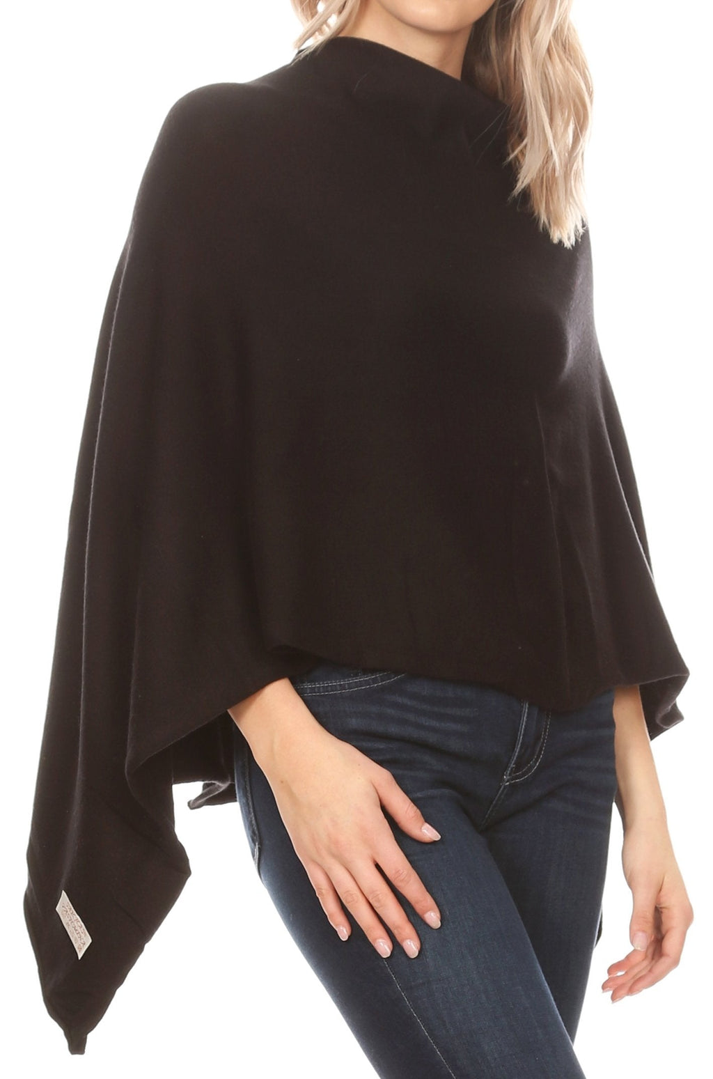 Black cape poncho pullover with loose drape sleeves and high neck over dark jeans