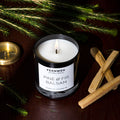 Pine & Fir Balsam scented soy candle with lit flame in black glass jar
