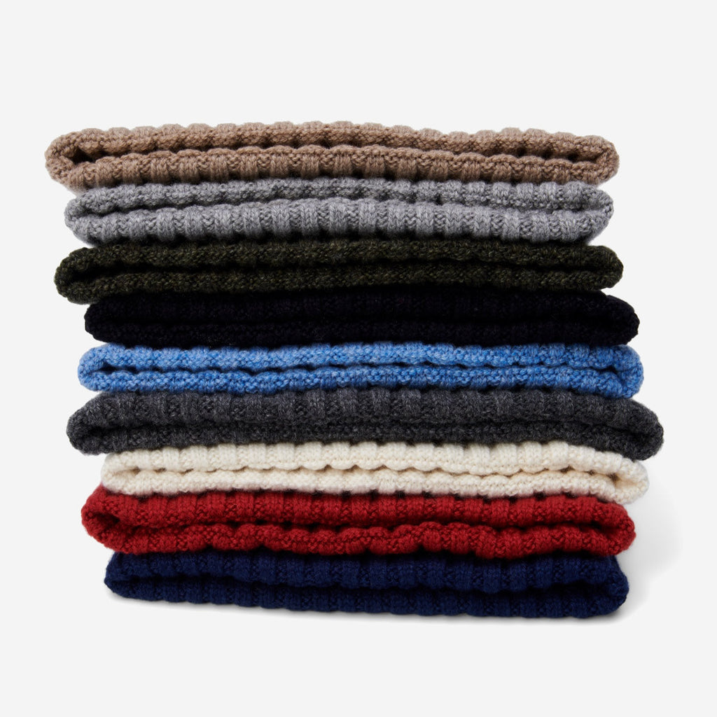 Stack of ribbed knit beanies in dark, light blue, cream, and red