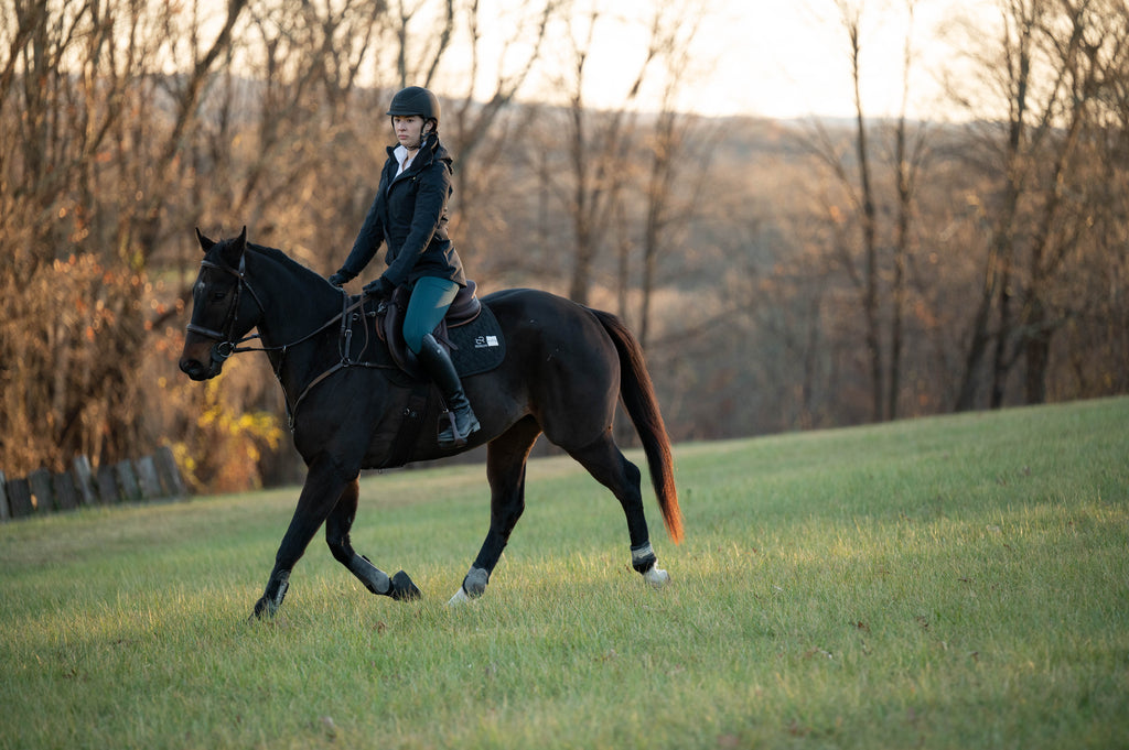 Black insulated riding jacket on rider with hood and front zipper
