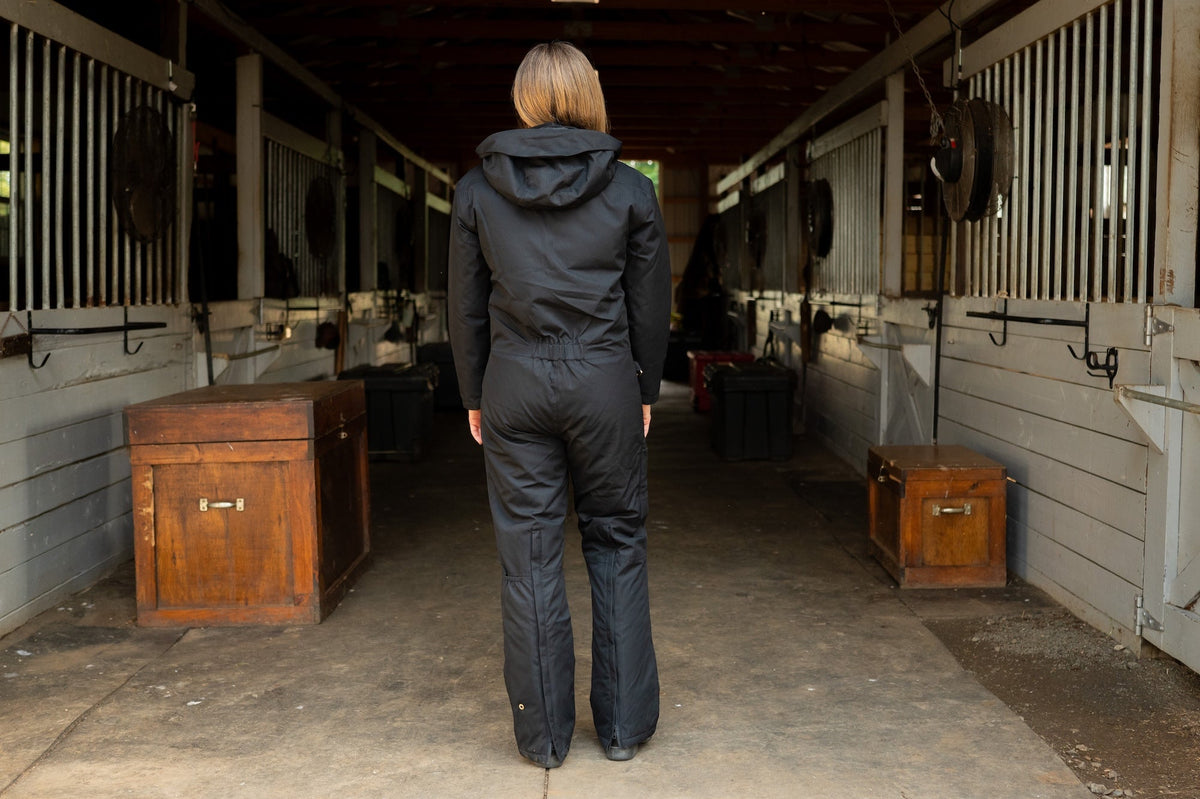 Rear view of dark insulated hooded jumpsuit with hood up and vertical back seams
