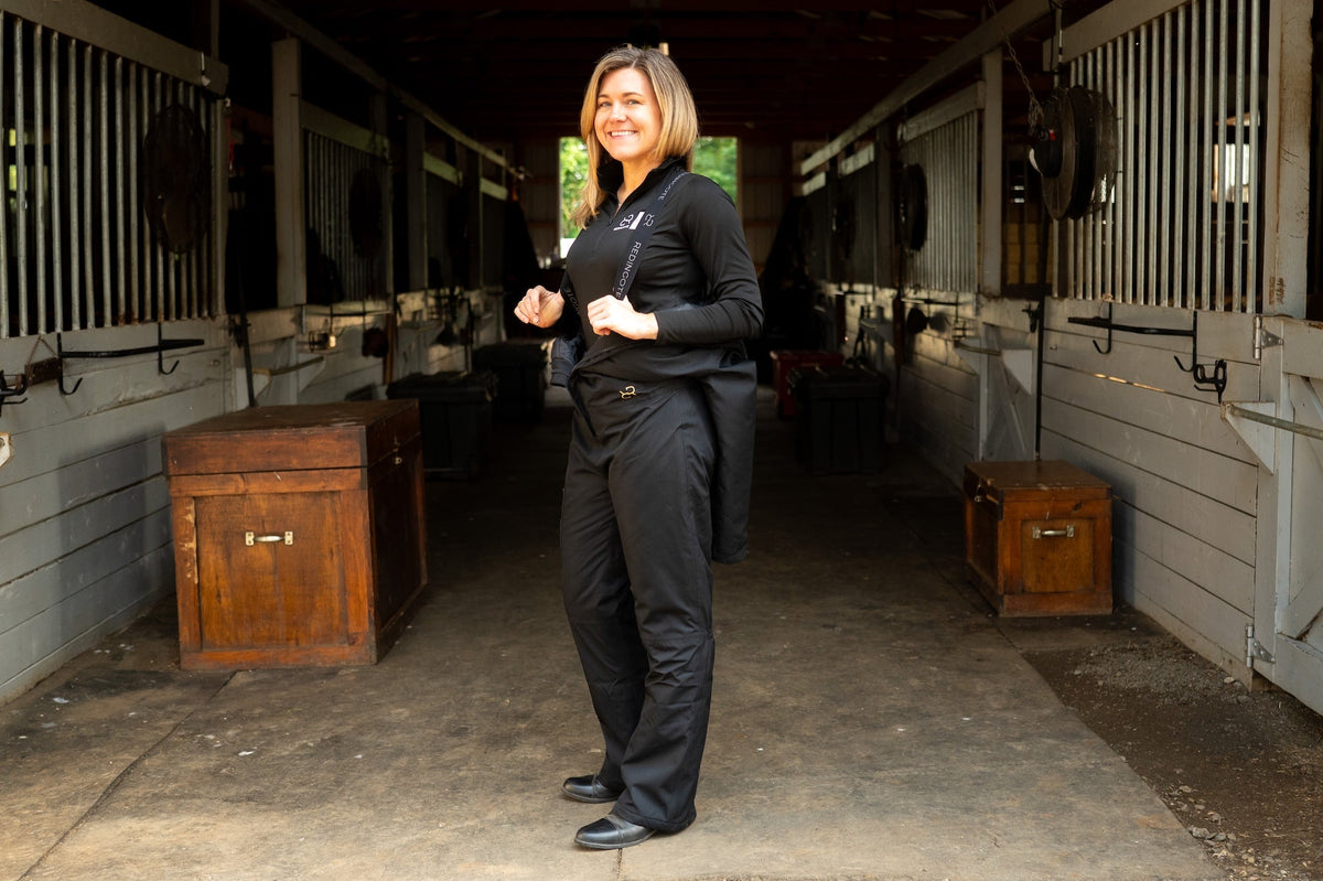 Insulated dark hooded jumpsuit worn with front zipper and long sleeves, standing pose