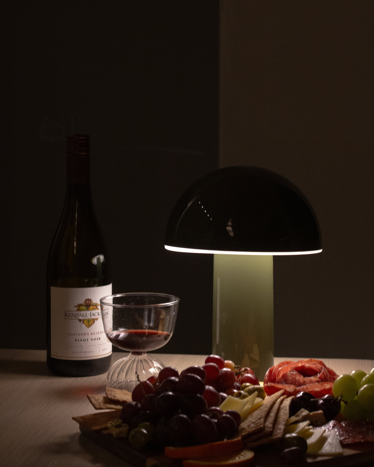 Black portable lamp with dome shade and tall cylindrical base, glowing light