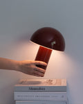 Red portable lamp with dome shade and cylindrical base, warm light glow