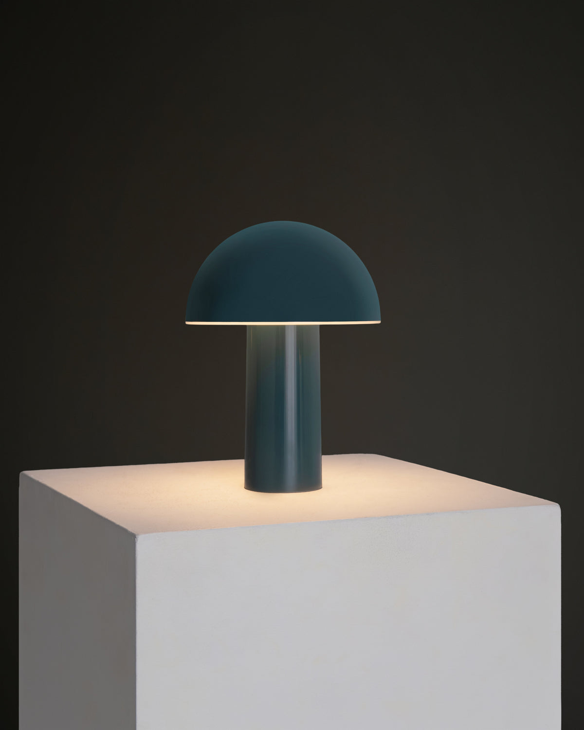 Teal portable lamp with dome shade and cylindrical base, warm light glow