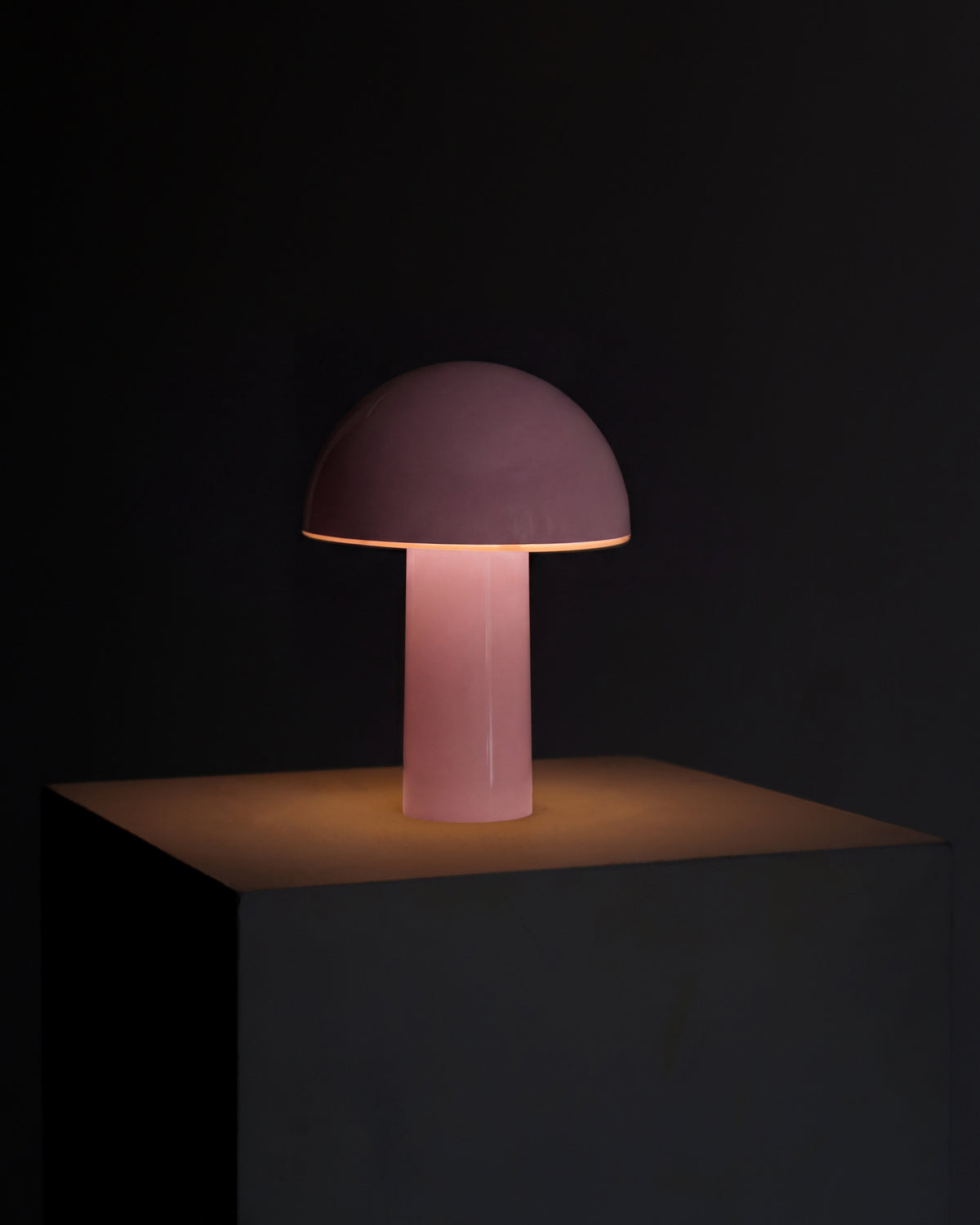 Pink portable lamp with dome shade and tall cylindrical base, soft warm light