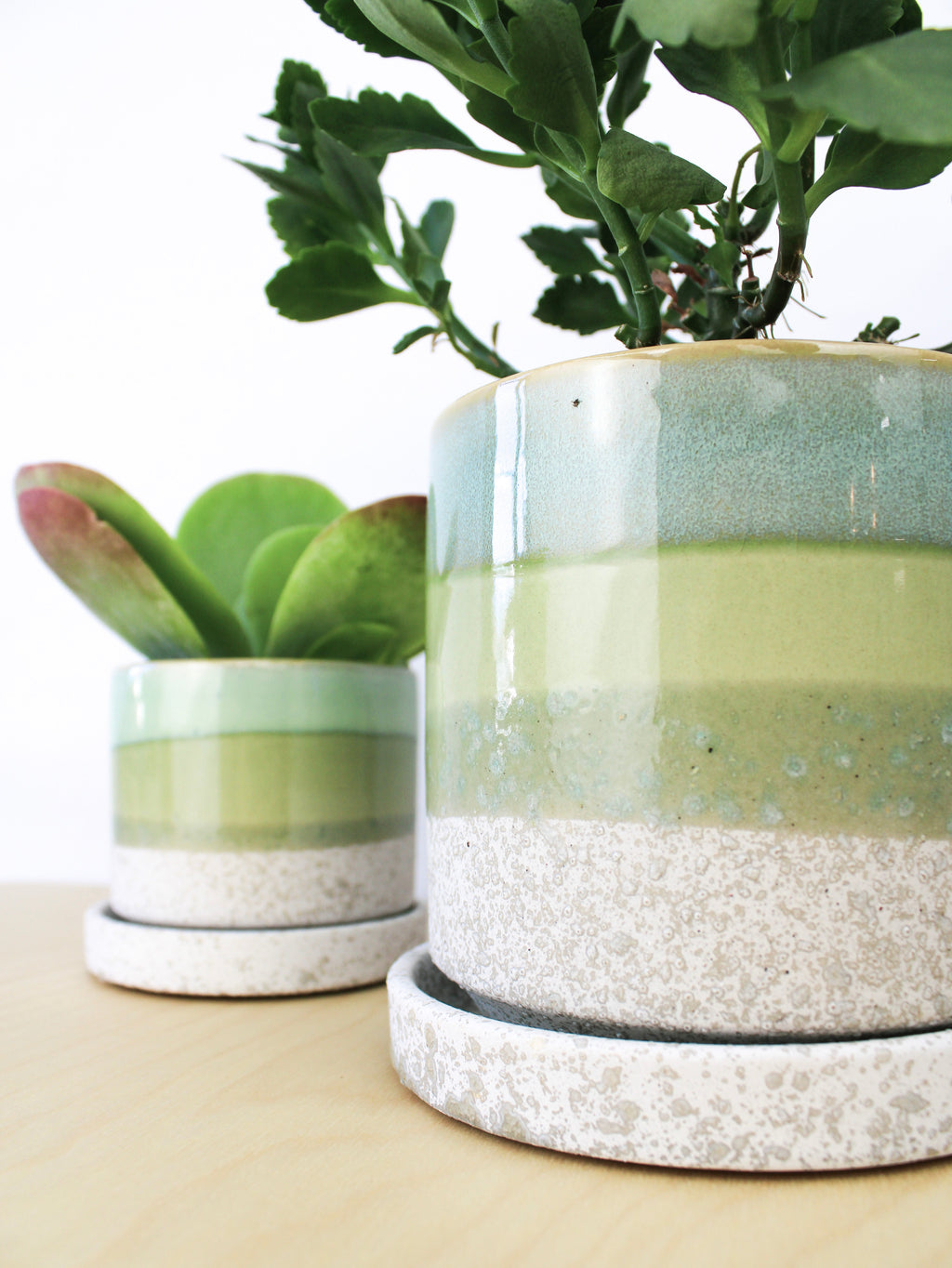Two ceramic plant pots and saucers with cement green glaze and speckled bases