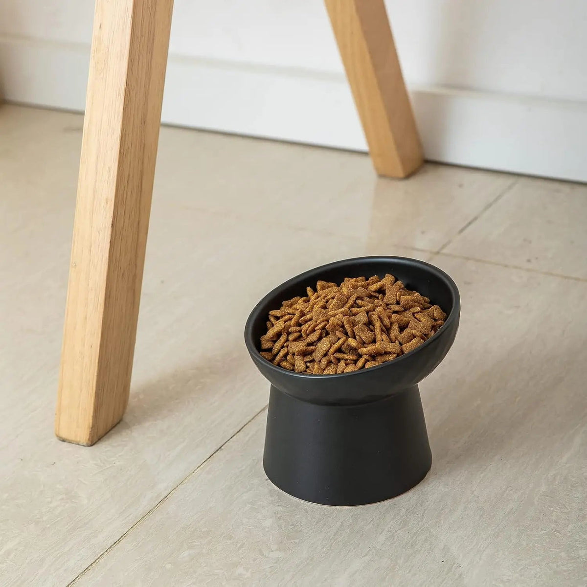 Black raised tilted ceramic cat bowl with kibble