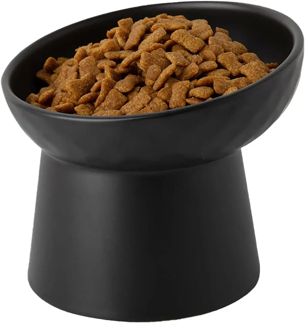Black raised tilted ceramic cat bowl filled with kibble pellets