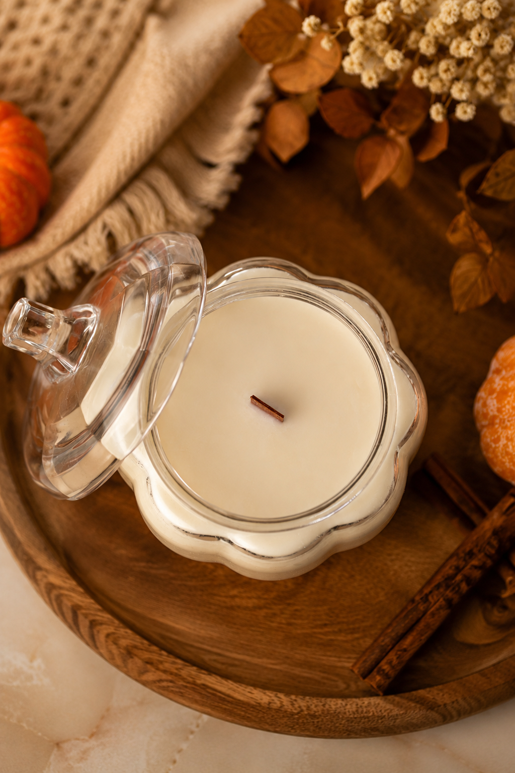 Clear glass candle jar with cream wax, lid ajar and wick visible from above