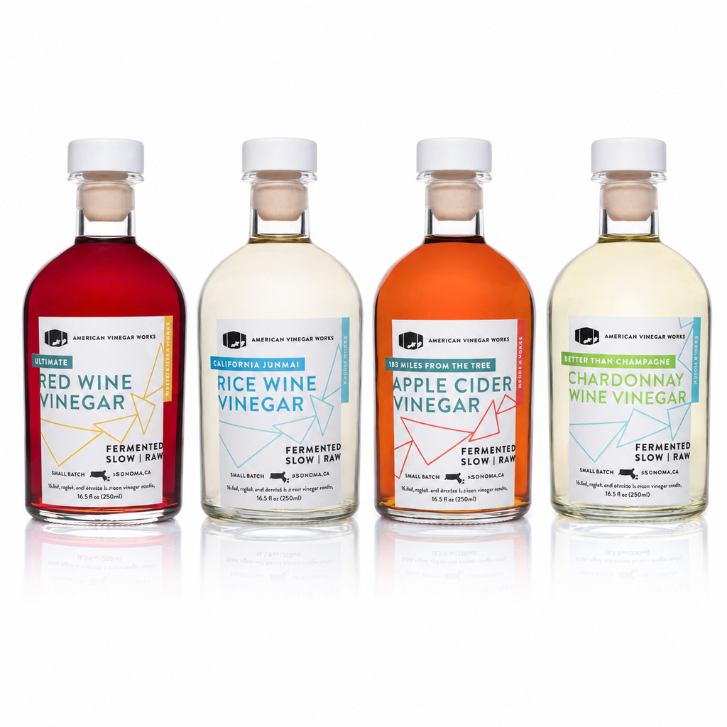 Row of four vinegar bottles with white caps and colored labels.