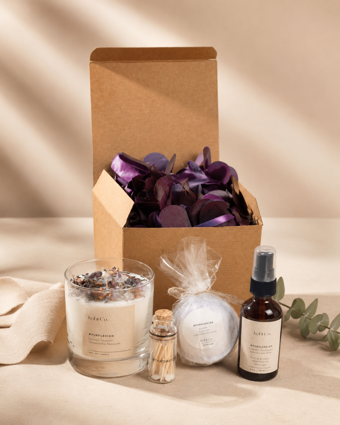 Gift box with purple filler, glass candle jar, bath products, and mist spray bottle