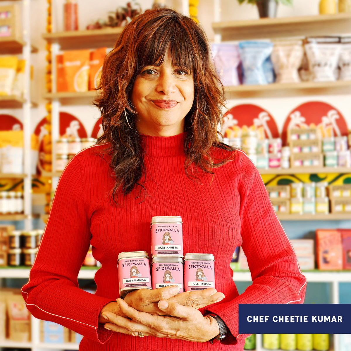 Chef Cheetie Kumar holding rose harissa spice tins in a store aisle