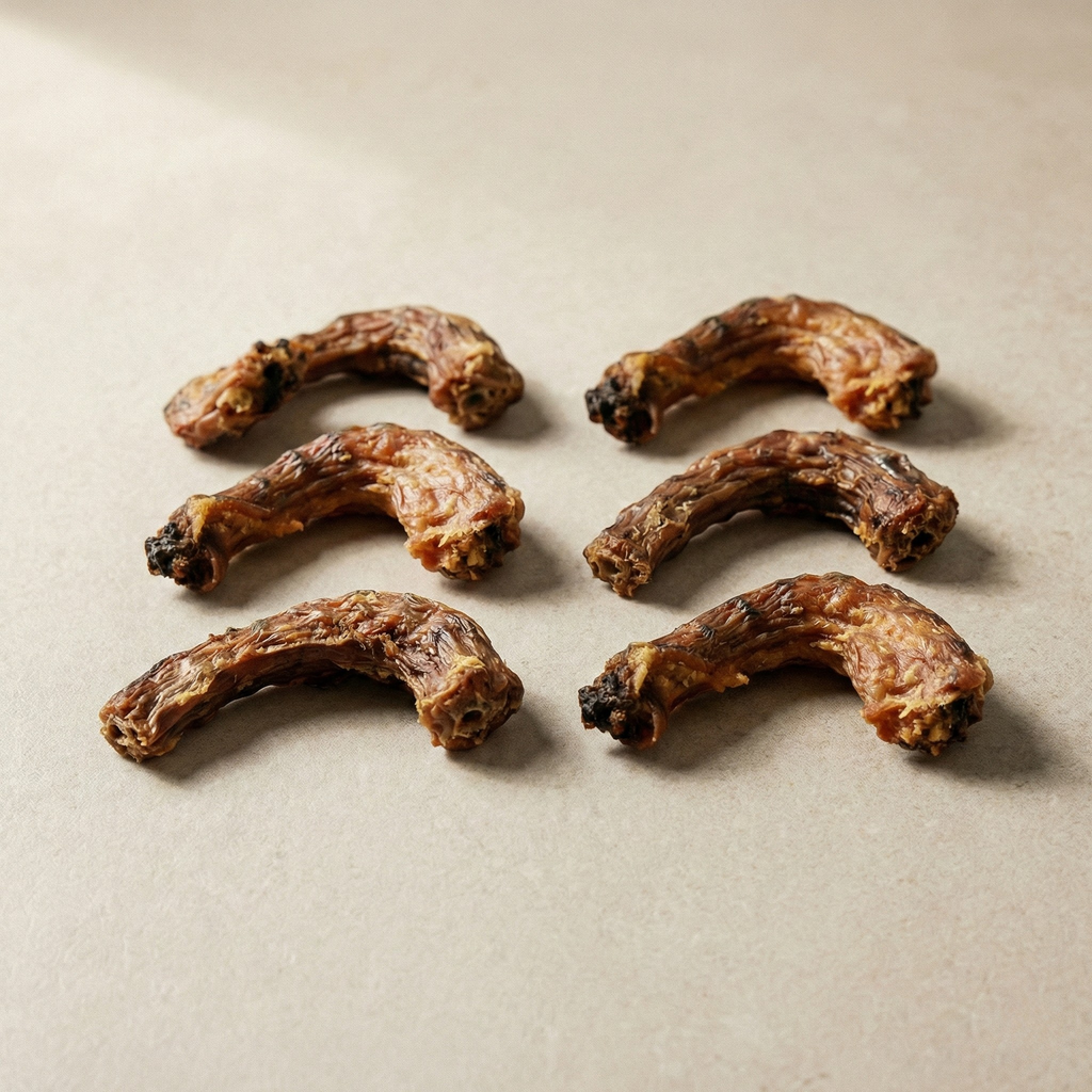 Dried chicken neck treats arranged on a light beige surface