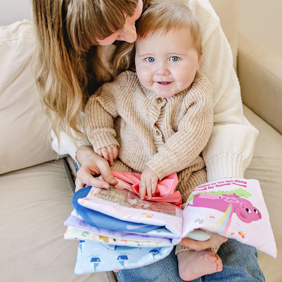 Baby holding stacked photo-pocket storybook albums with pink and blue covers