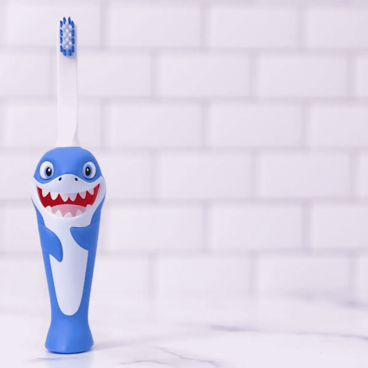 Blue shark kids toothbrush with white bristles and cartoon smiling shark face