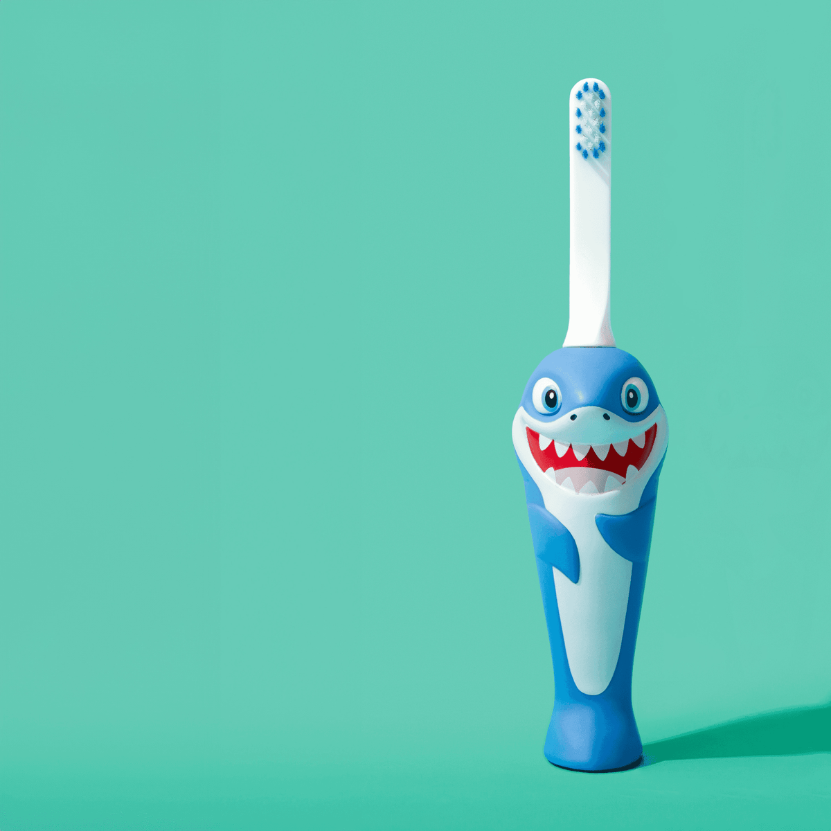 Angled blue shark kids toothbrush with white bristles and cartoon shark face