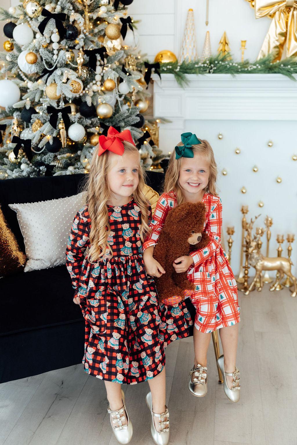 Two girls wearing red-and-blue plaid long-sleeve twirl dresses with bear prints