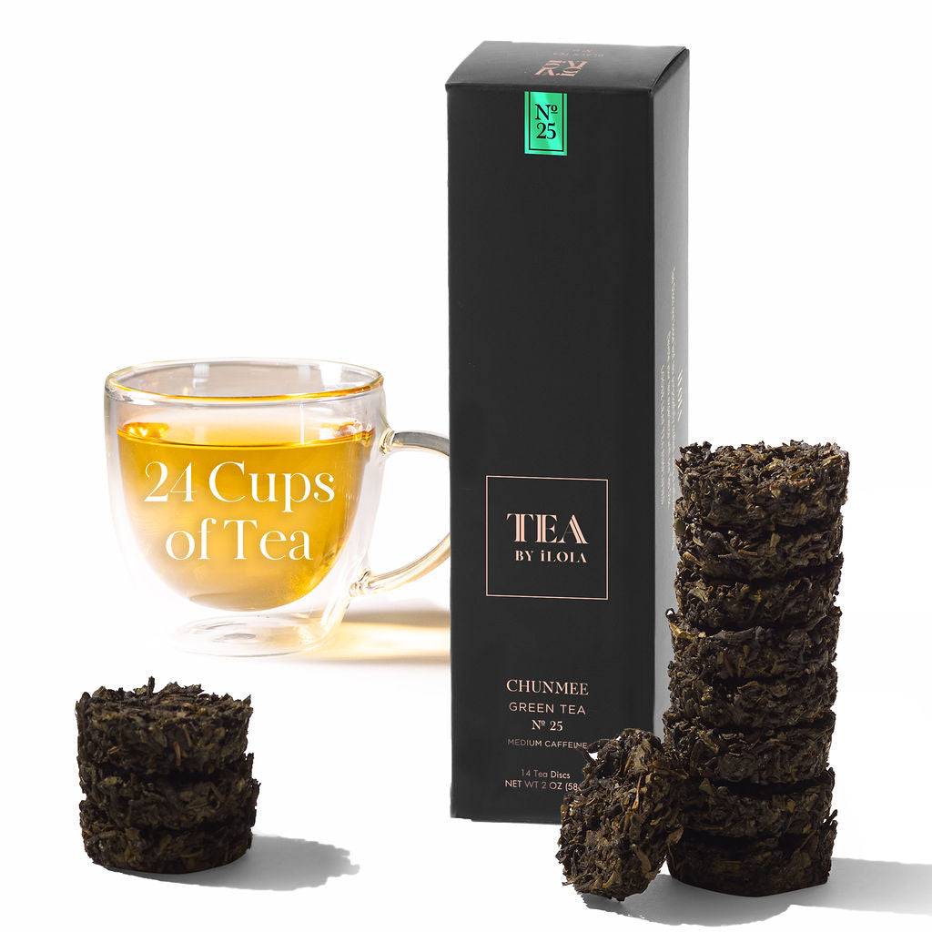 Chunmee green tea box and compressed tea discs beside a cup of brewed tea