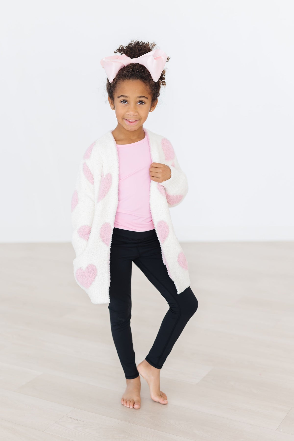 Light pink heart cozy cardigan with fuzzy white knit and light pink heart pattern, open front.