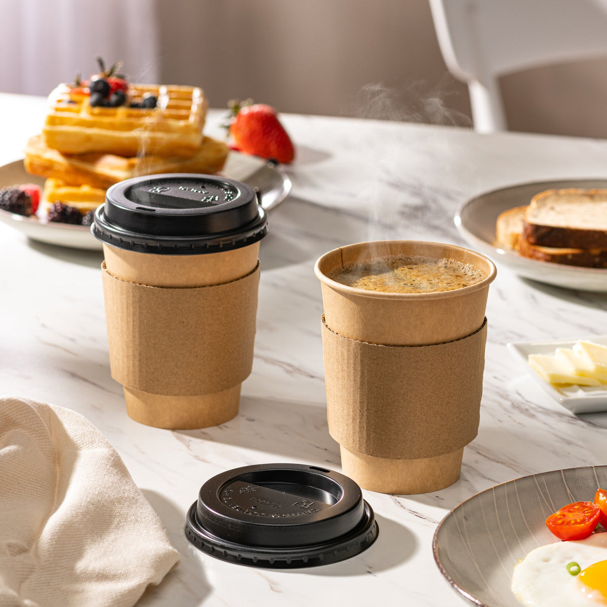 Kraft paper coffee cups with black lids and sleeves filled with hot coffee