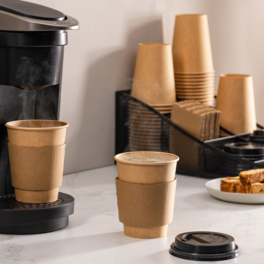 Multiple kraft paper coffee cups with black lids and stacked sleeves
