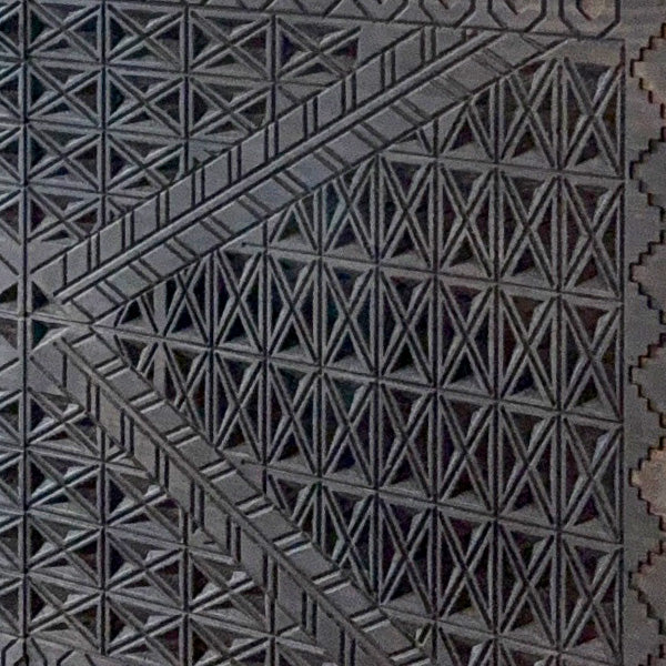 Close-up of carved geometric pattern on dark wood console table front