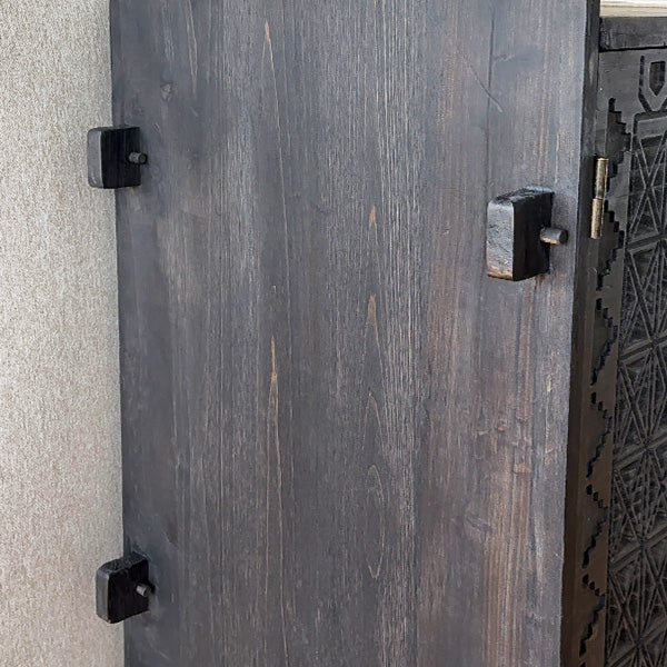 Close-up of dark wood cabinet door hardware on carved console table