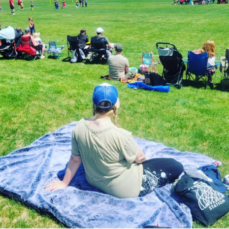 Large outdoor blanket in light blue with a rolled-up carrying bundle.