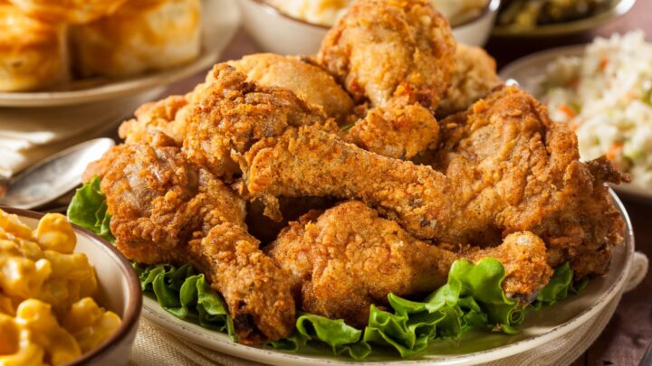 Golden fried chicken pieces on lettuce, served on a plate with sauce in background