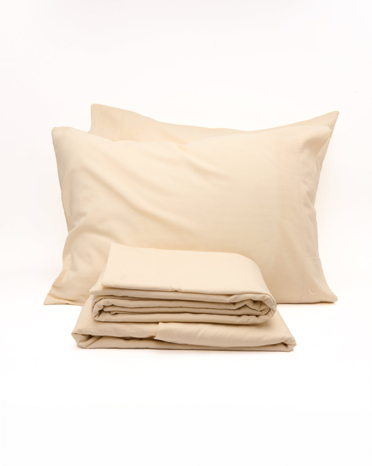 Cream pillowcases stacked with folded sheets underneath