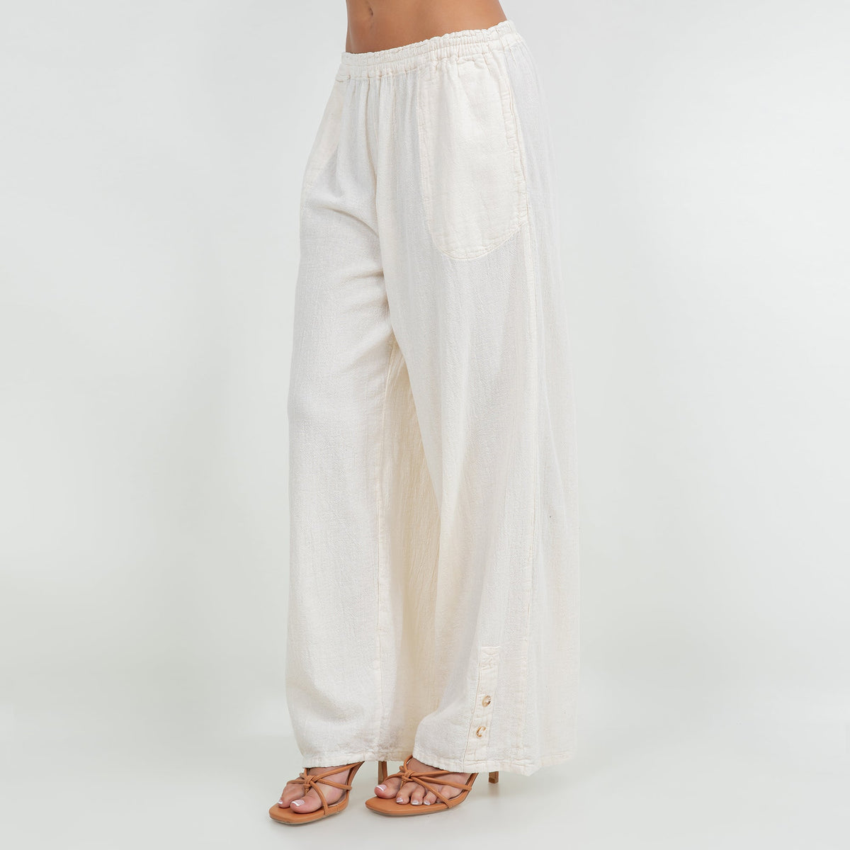 Ivory cotton gauze pants with elastic waistband, wide legs, and side button details
