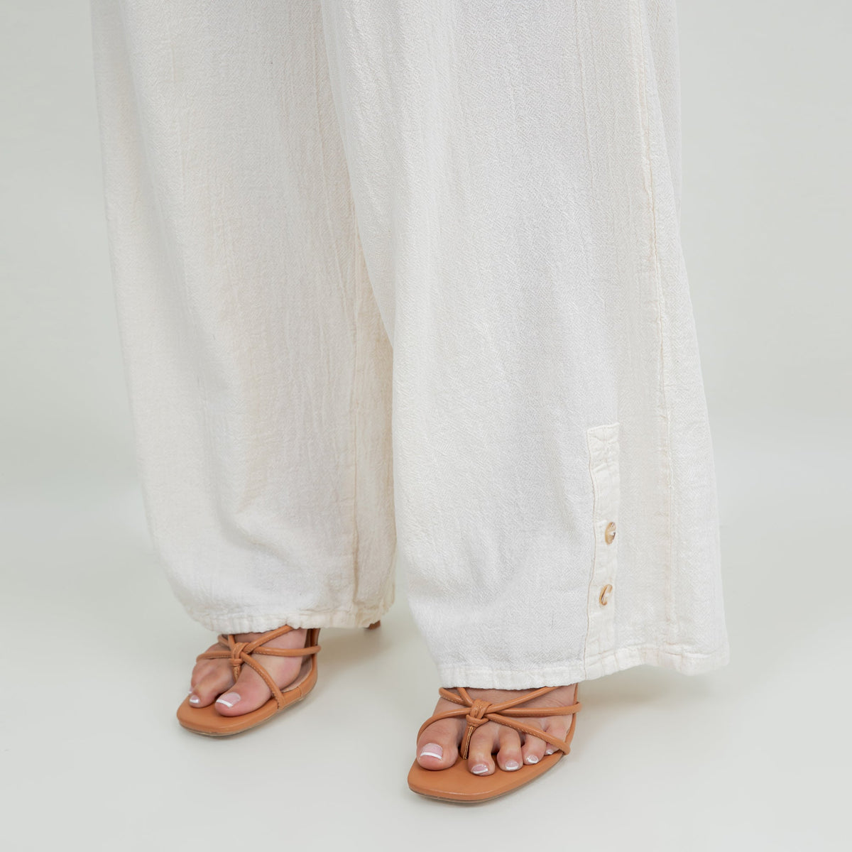 White cotton gauze pants detail: elastic waist and buttoned hem