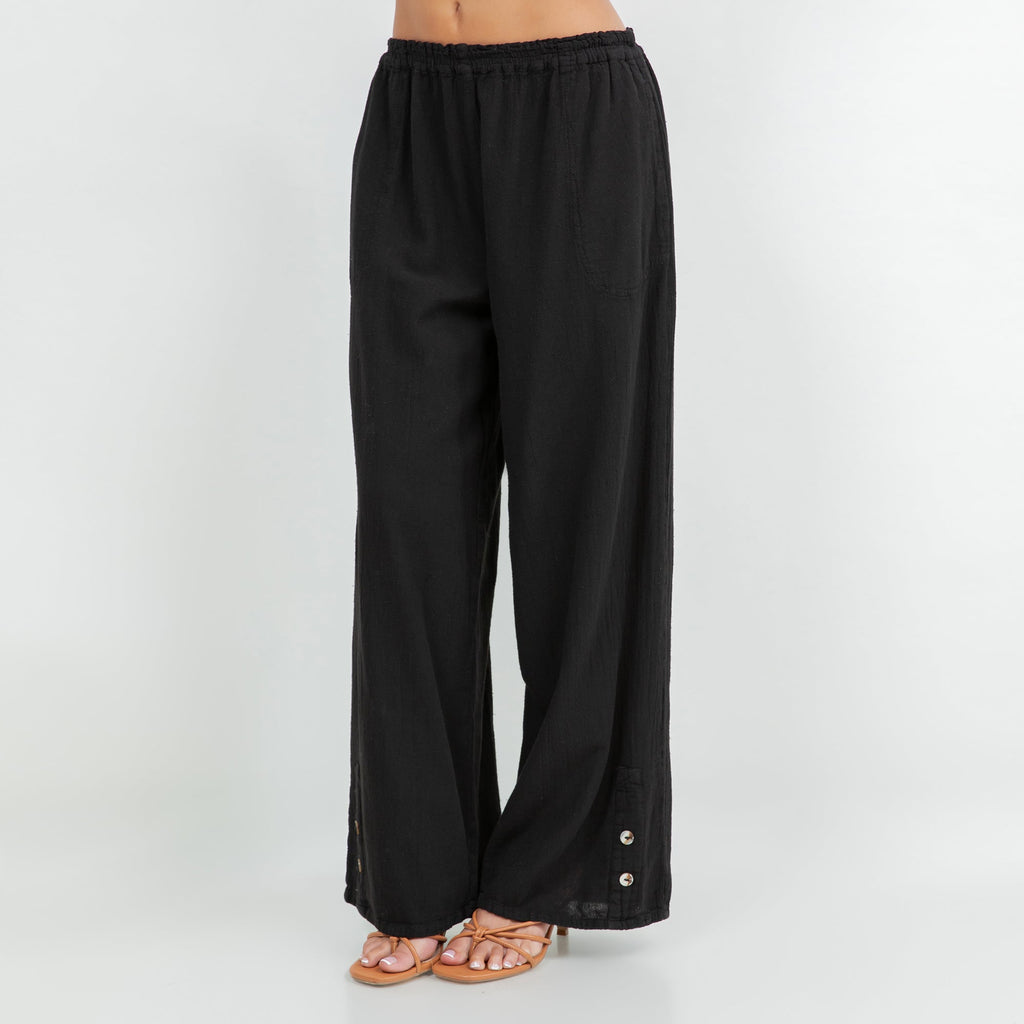 Black cotton gauze pants with elastic waist, loose wide-leg shape, and button-trim hem