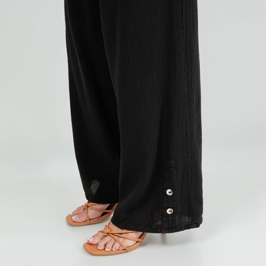 Black cotton gauze pant leg with side button placket at hem and relaxed drape