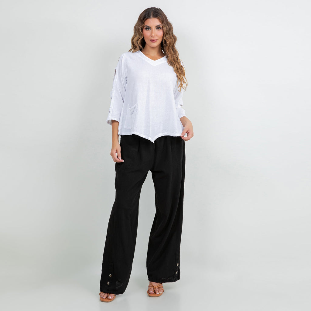 Black cotton gauze pants with elastic waist, wide-leg fit, and button accent near hem