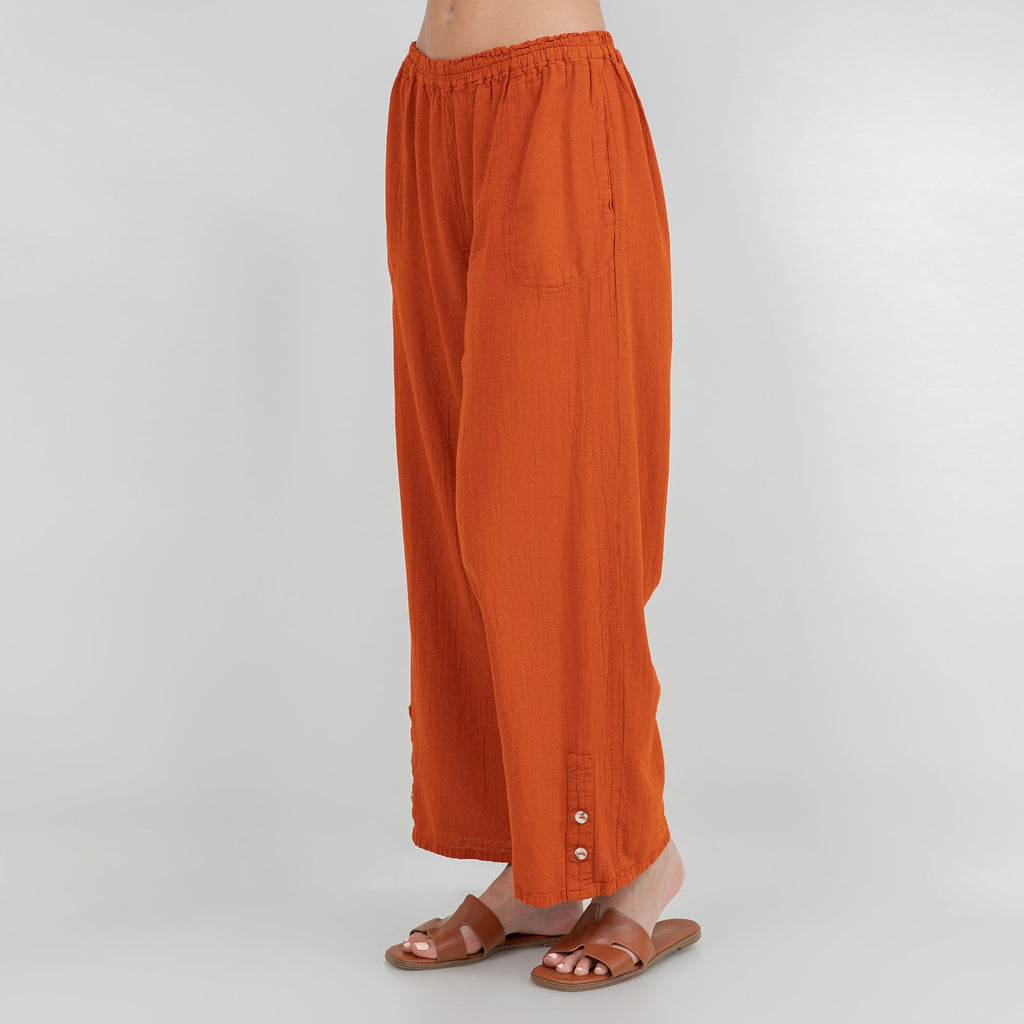 Orange cotton gauze pants with elastic waistband, loose wide leg, ankle length, button detail at hem